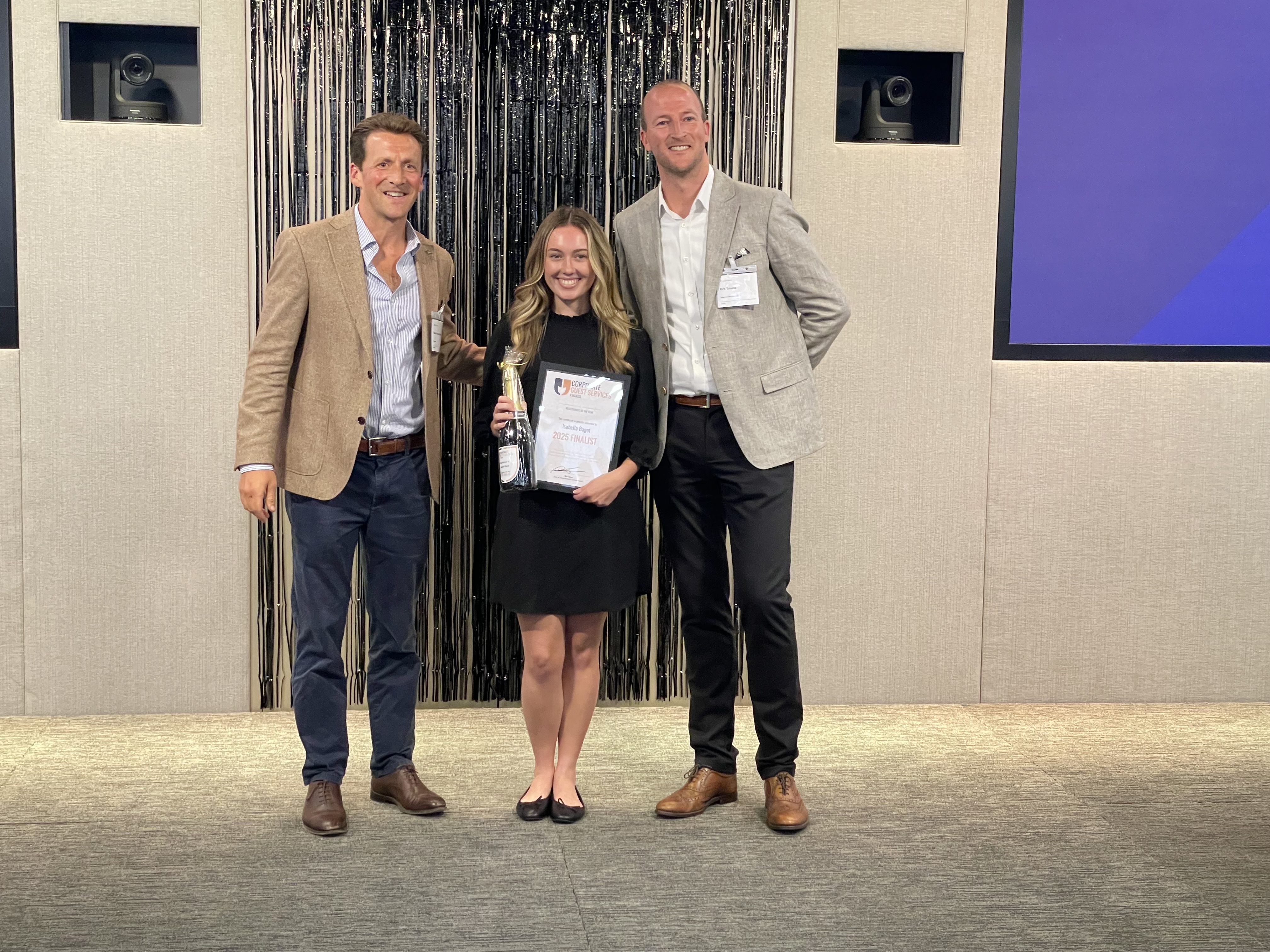 Isabella, Securitas STARS security officer 2025 finalist for corporate guest services, holding a certificate and a champagne bottle.